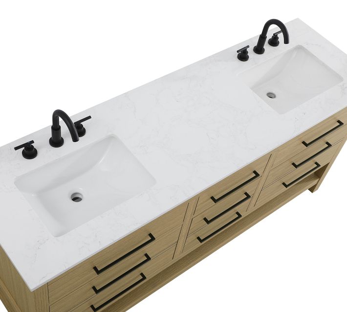Close-up of a white marble-like countertop with two basins and black faucets.