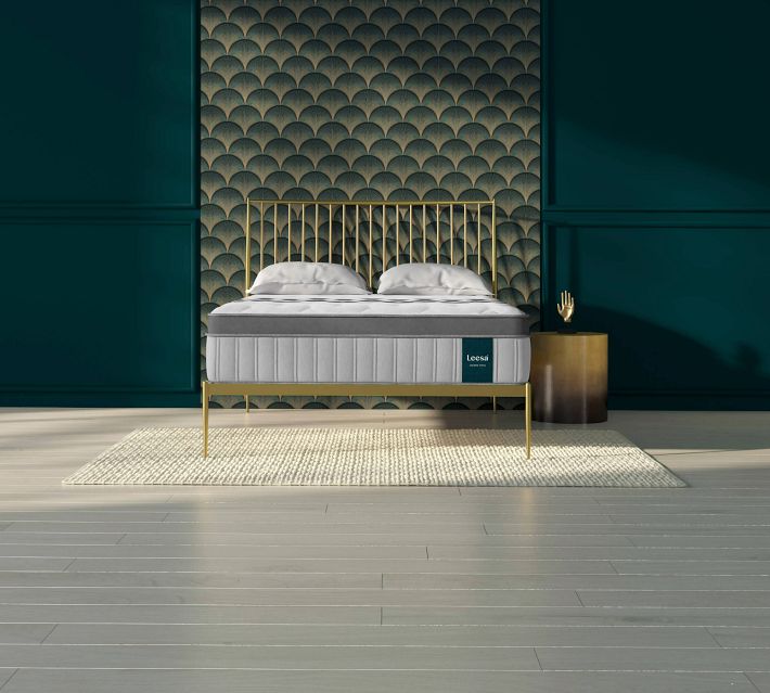 Gold metal bed frame with gray upholstered mattress on a light rug in a stylish bedroom