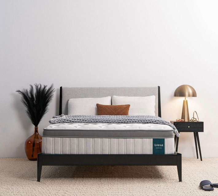 Bedroom setup with bed, nightstand, lamp, and decorative plant