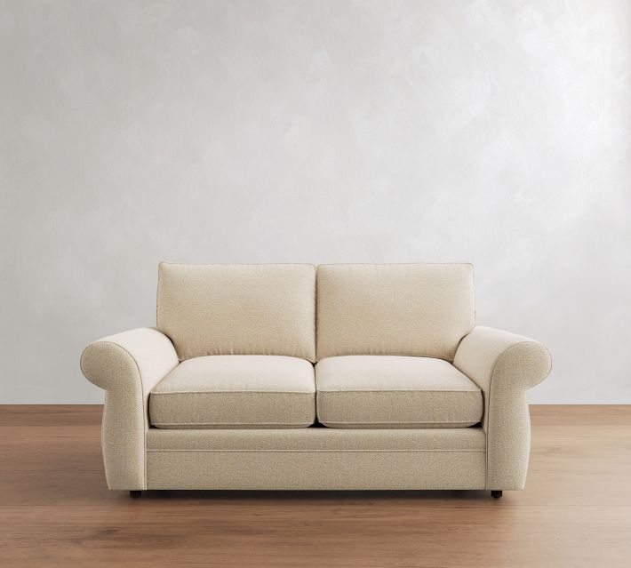 Beige three-seater sofa with two-seat cushions and rolled armrests from front.