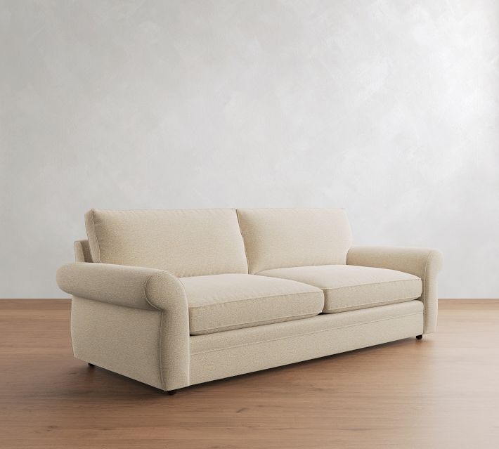 Beige sofa with three cushions and wooden floor.