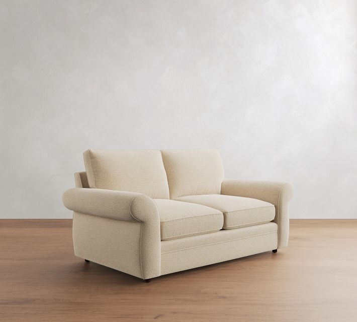 Beige loveseat from a slightly different angle highlighting armrest and cushions.