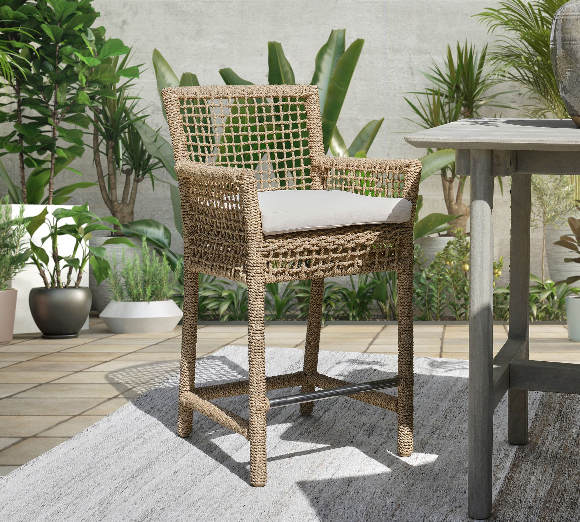 Single woven rope bar stool placed next to table