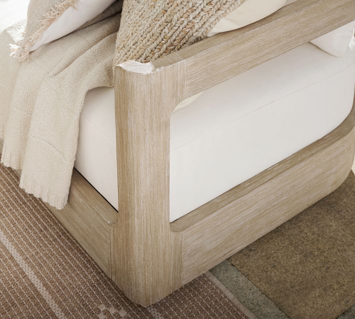 Wooden arm of a sofa with light beige upholstery and visible wood grain