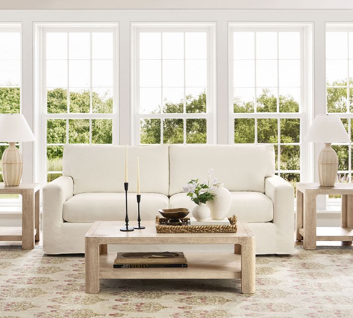 Bright living room with white sofa and large windows, coffee table