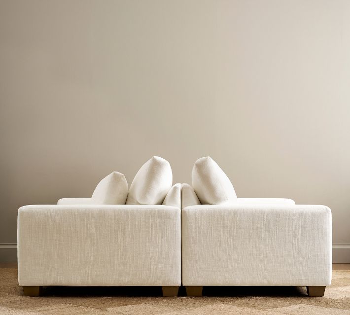 Two-seater sofa with white upholstery and multiple cushions in living room