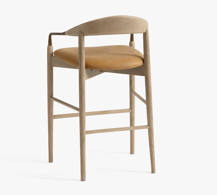 Three-quarter view of tall bar stool with brass armrest