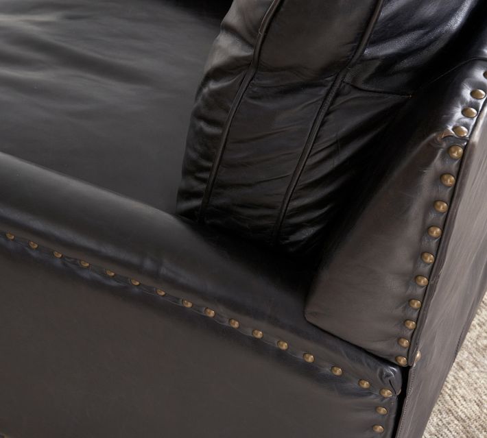 Close-up of studded nailhead trim along a black leather armchair.