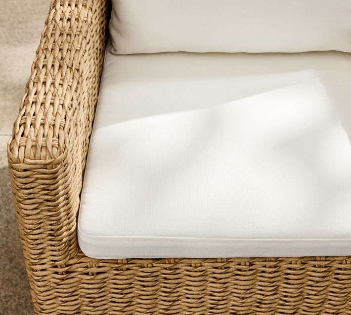 Close-up of beige cushion on wicker chair showing woven texture