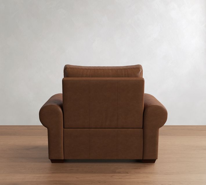 Back view of a brown leather armchair revealing the back cushions and stitching.