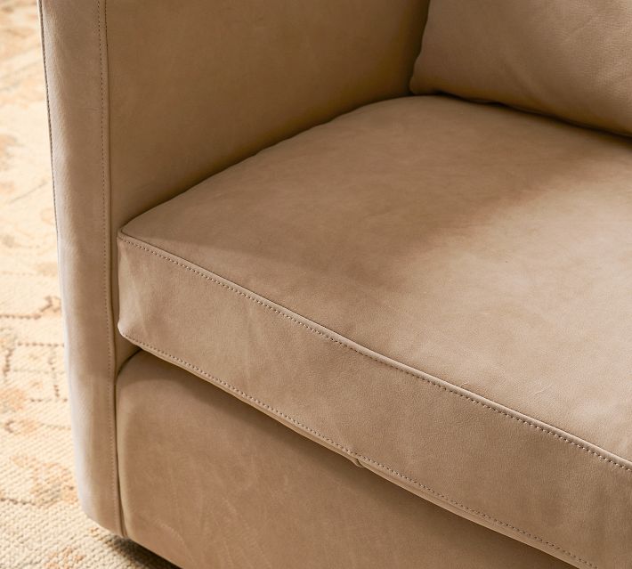 Close-up of tan leather upholstered armchair arm and seam