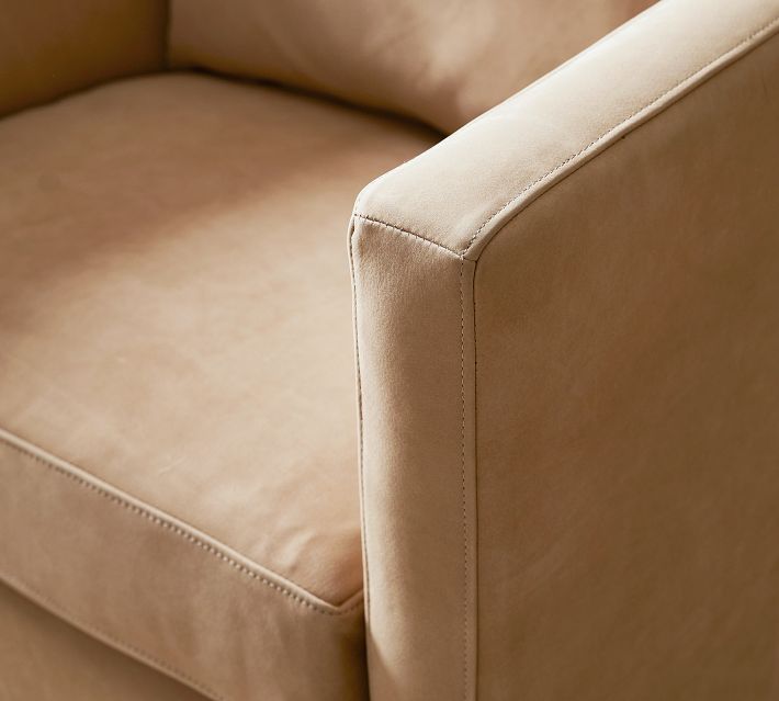 Corner of tan leather armchair showing arm and seam