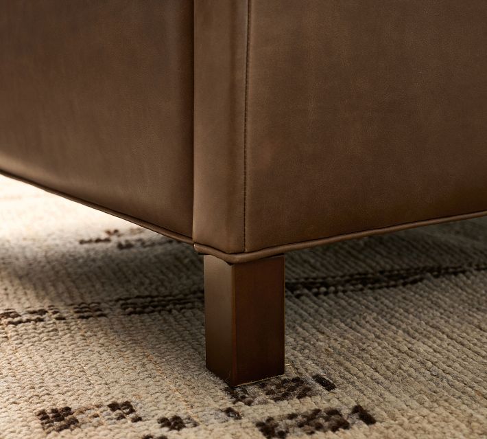 Bottom corner of the chair with wooden leg and base on rug.