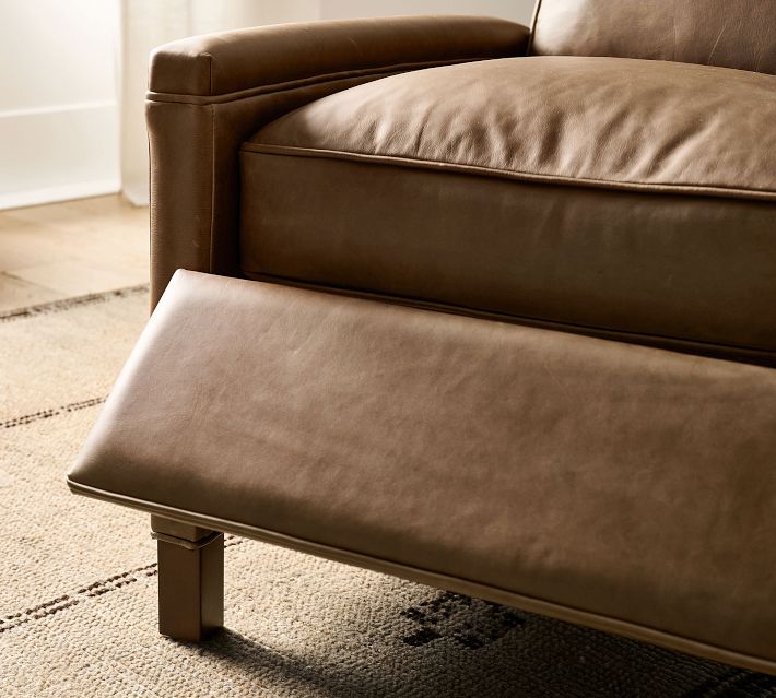 Close-up of the brown leather seat and extended footrest with soft cushions.