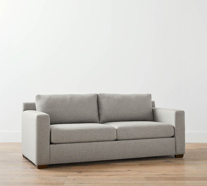 Two-seater gray fabric sofa from a side angle with two back cushions and wide armrest