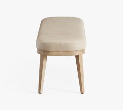 Dining bench in light beige with wooden legs on white.